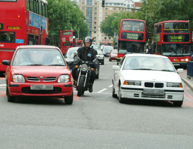 If those cars aren't moving quickly the the grey area has gone - this biker is NOT breaking the law any more...